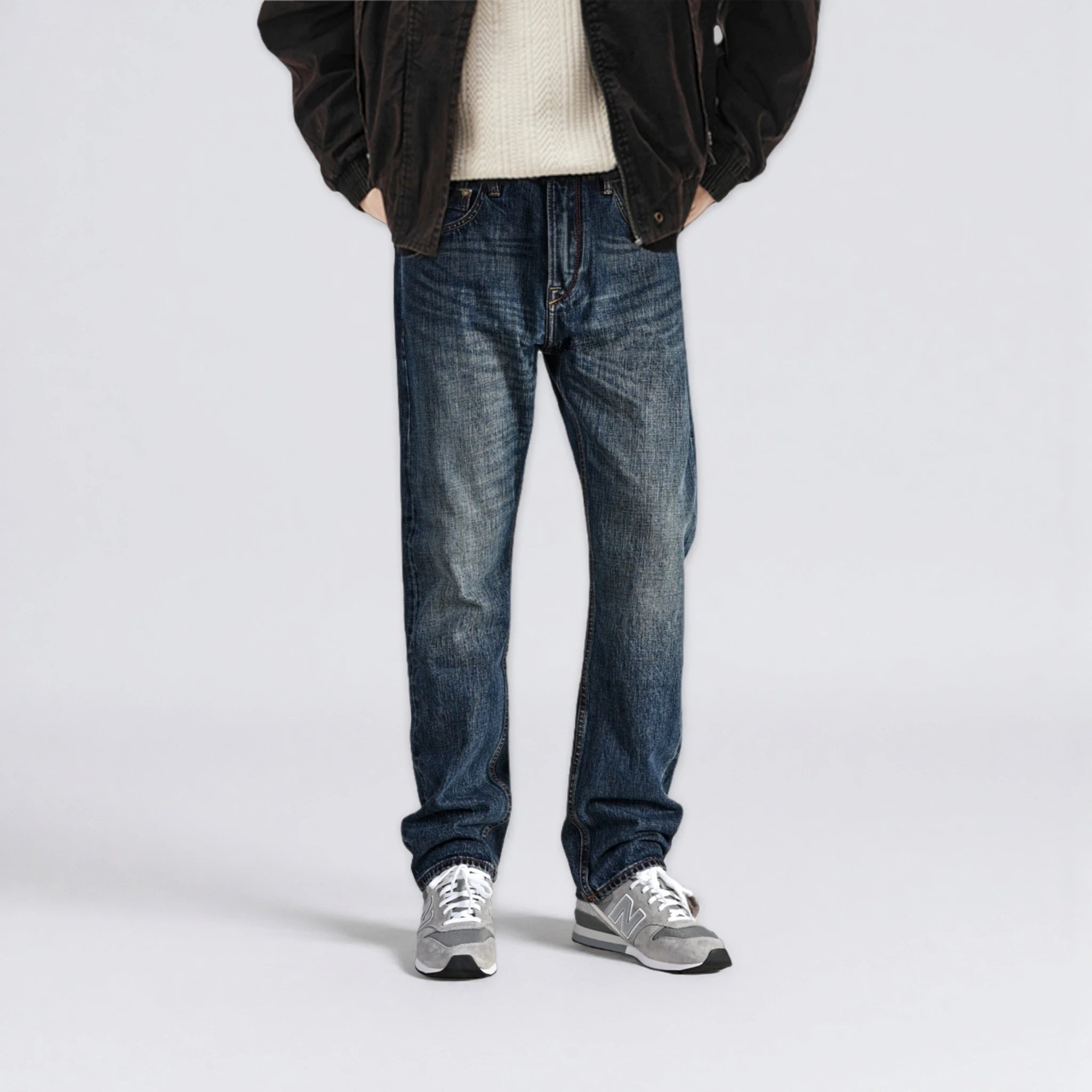 Person wearing blue jeans and a dark jacket on a light gray background