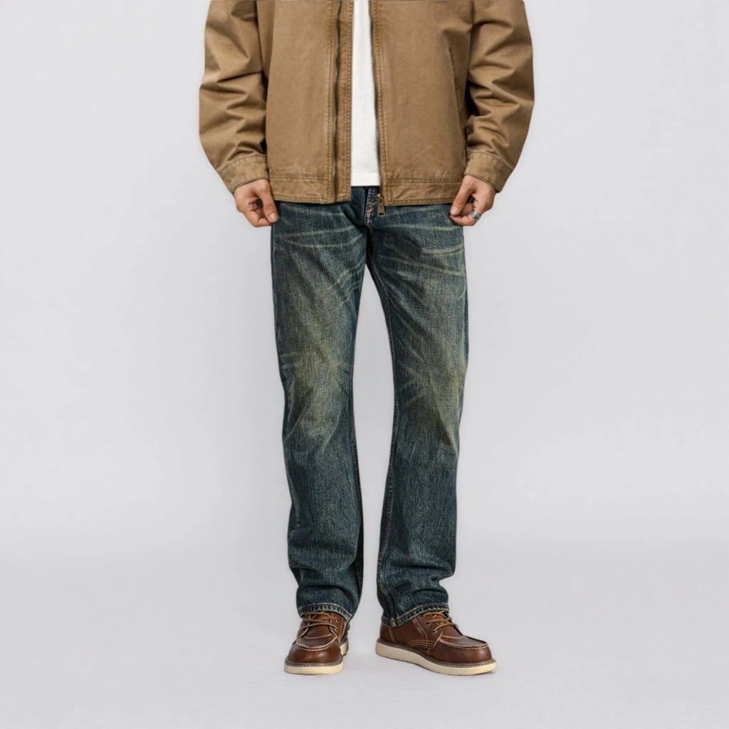 Person wearing a brown jacket, white shirt, blue jeans, and brown shoes on a light gray background