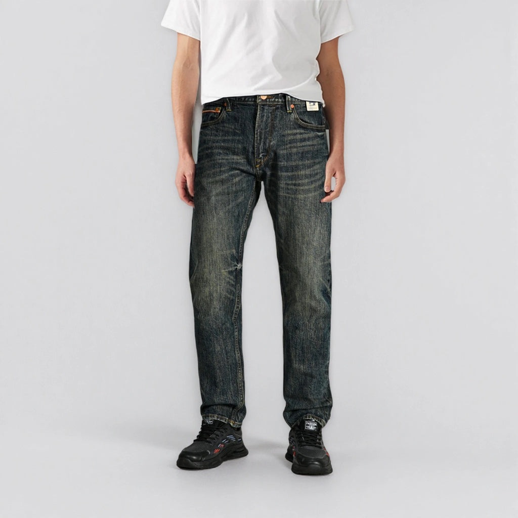 Person wearing dark blue jeans and a white t-shirt on a plain background