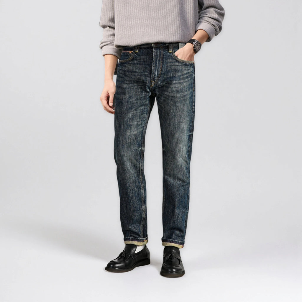 Person wearing blue jeans and a gray sweater on a white background