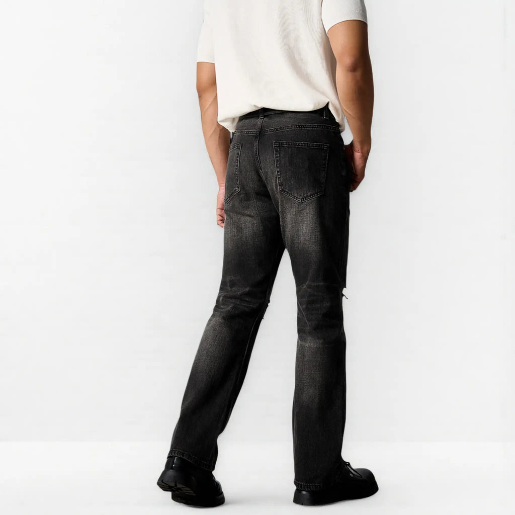 Person wearing black distressed jeans and a white shirt on a white background