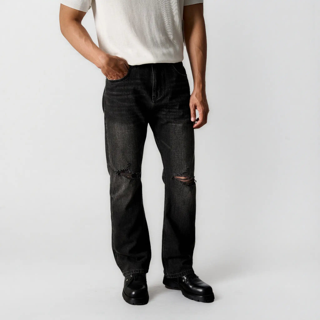Person wearing black distressed jeans on a white background
