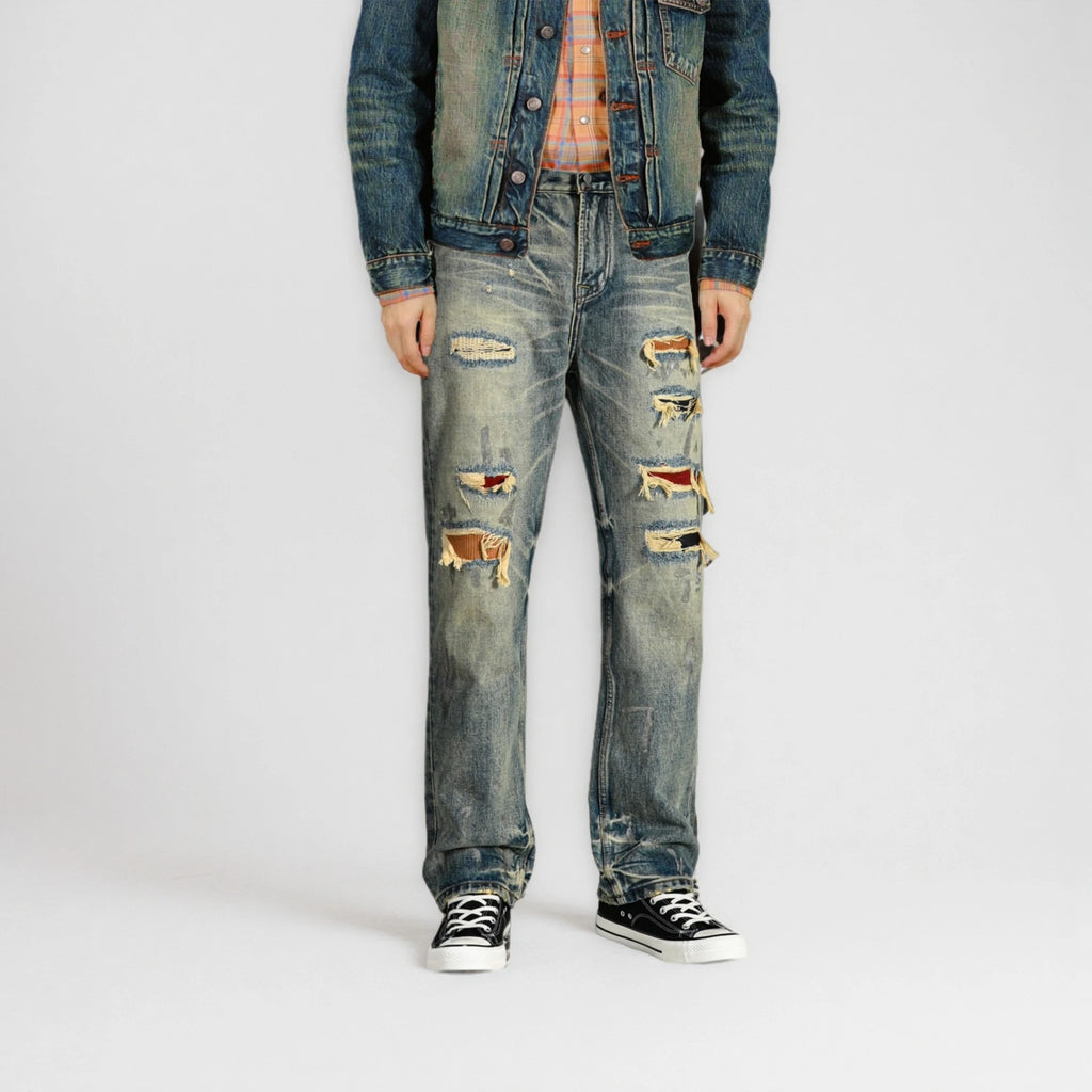 Person wearing distressed blue jeans and a denim jacket on a white background