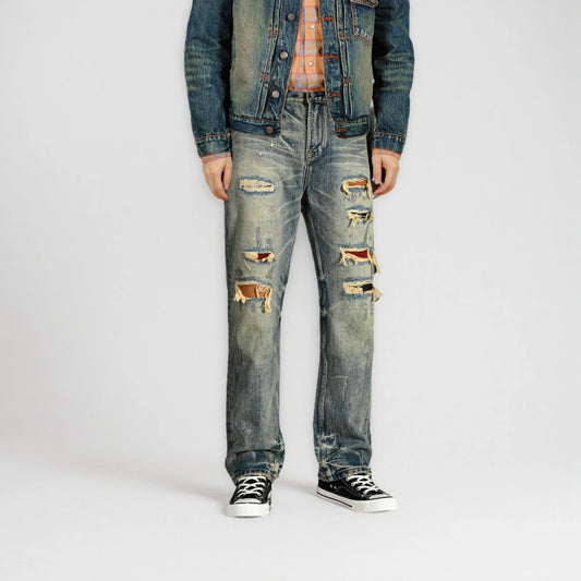 Person wearing distressed blue jeans and a denim jacket on a white background