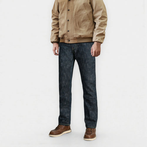 Person wearing a beige jacket, dark jeans, and brown shoes on a white background