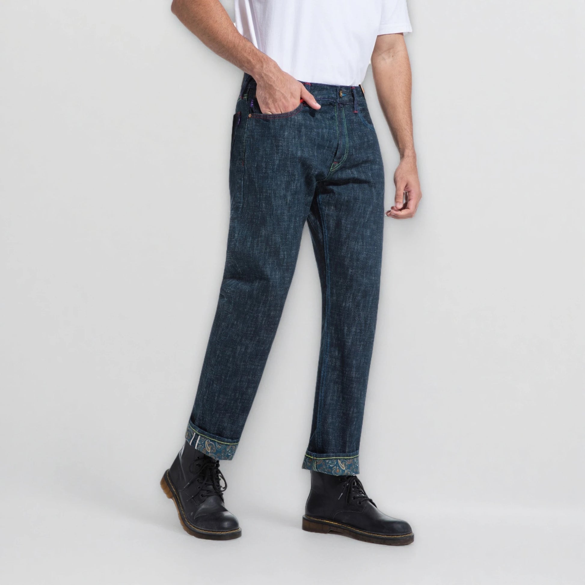 Person wearing dark blue jeans and black shoes on a light gray background