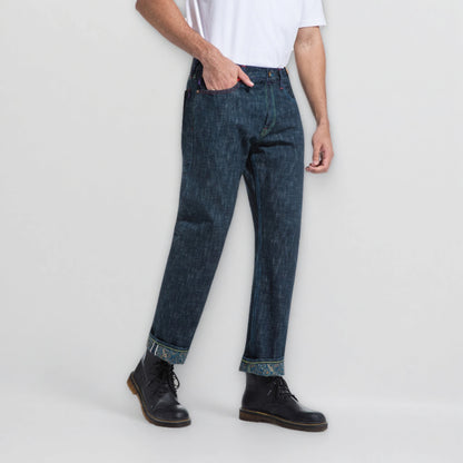 Person wearing dark blue jeans and black shoes on a light gray background
