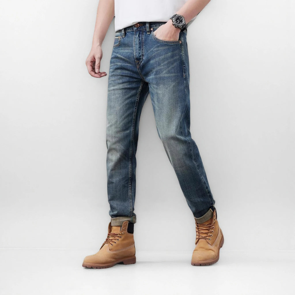 Person wearing blue jeans and tan boots on a white background